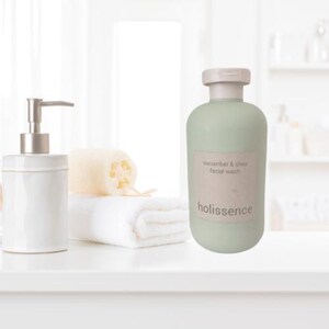 May include: A green plastic bottle of cucumber and shea facial wash with the brand name "holissence" printed on the label.