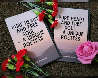 May include: Two book covers with the title "Pure Heart and Free Soul - A Unique Poetess" and the author's name "Aisha Idris Suleman". The covers are on a brown surface with red and pink flowers.