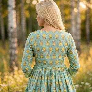 Teal green cotton print kurti for women with yellow floral block print design, handmade Indian ethnic tunic top with lace up neckline and tassel detail, soft breathable summer cotton kurta for casual daily wear, boho style printed kurti paired with black leggings, lightweight spring outfit for women, handcrafted floral cotton kurta for office wear and festive occasions, traditional Indian block print tunic with 3/4 sleeves, comfortable relaxed fit cotton kurti for vacation travel,