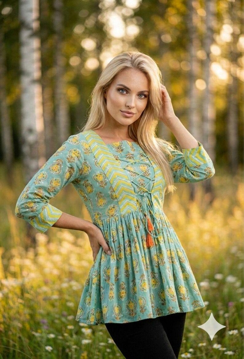 Teal green cotton print kurti for women with yellow floral block print design, handmade Indian ethnic tunic top with lace up neckline and tassel detail, soft breathable summer cotton kurta for casual daily wear, boho style printed kurti paired with black leggings, lightweight spring outfit for women, handcrafted floral cotton kurta for office wear and festive occasions, traditional Indian block print tunic with 3/4 sleeves, comfortable relaxed fit cotton kurti for vacation travel,