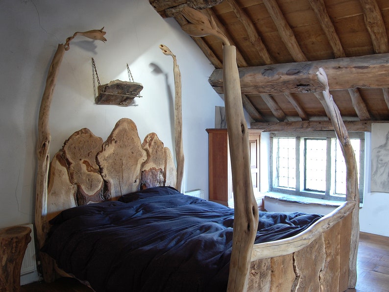 May include: A rustic wooden bed frame with a headboard made of large, natural wood slabs. The bed is covered with a dark blue duvet and has a wooden shelf above the headboard.