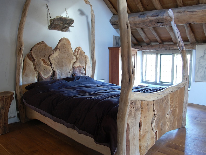 May include: A rustic wooden bed frame with a headboard made of thick, natural wood slabs. The bed is covered with a dark blue duvet and has a simple, natural design.