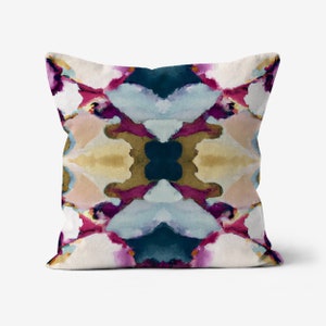 May include: A decorative throw pillow with a colorful abstract design featuring shades of pink, blue, teal, and gold. The pattern is symmetrical and resembles a watercolor painting.