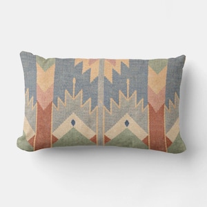 May include: Rectangular throw pillow with a geometric pattern in shades of blue, green, peach, and red. The design features repeating arrow and diamond shapes. The pillow has a soft, textured appearance.