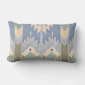 May include: Rectangular decorative pillow with a geometric pattern in shades of blue, green, and cream. The design features repeating arrow-like shapes and diamond accents, creating a Southwestern or tribal aesthetic.