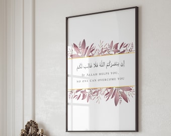 Può includere: Una stampa incorniciata bianca con un bordo dorato e accenti floreali rosa. La stampa presenta una citazione araba in testo nero che si traduce in "Se Allah ti aiuta, nessuno può superarti."