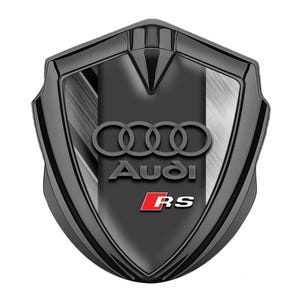 Può includere: Stemma Audi RS nero e argento con quattro anelli intrecciati e la parola "Audi" in lettere bianche sotto gli anelli. La parola "RS" è in lettere rosse sotto la parola "Audi".