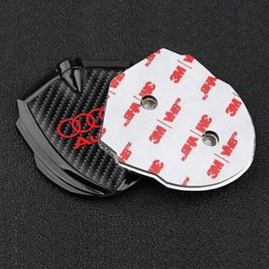 May include: Black carbon fiber car emblem with a red Audi logo and a silver backing with 3M VHB tape.