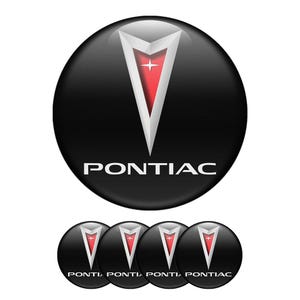 May include: A set of five black and silver Pontiac car badges. Each badge features a red and silver arrowhead logo with the word "PONTIAC" written in white below it.