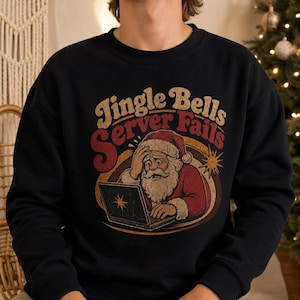 May include: A black crewneck sweatshirt featuring a graphic of Santa Claus looking stressed while using a laptop. The text above reads Jingle Bells Server Fails in a vintage-style font. The design uses red, gold, and white colors.