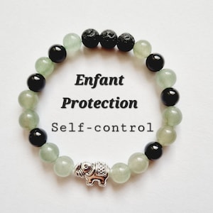 Puede incluir: Un brazalete de cuentas verdes y negras con un dije de elefante plateado. El brazalete tiene las palabras "Enfant Protection Self-control" escritas en él.