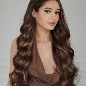 May include: A woman with long, wavy, brown hair wearing a brown halter top.