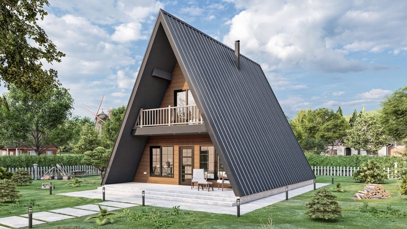 May include: A modern, A-frame house with a black metal roof and wooden siding. The house has a balcony on the second floor and a patio with chairs on the ground floor. The house is surrounded by green grass and trees.