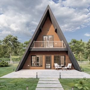 May include: A modern, wooden A-frame house with a balcony and a patio. The house is surrounded by green grass and trees.