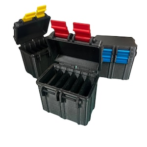 May include: Three black plastic storage cases with different colored latches. The case in the center is open and has multiple compartments inside. The case on the left has a yellow latch and the case on the right has a blue latch.