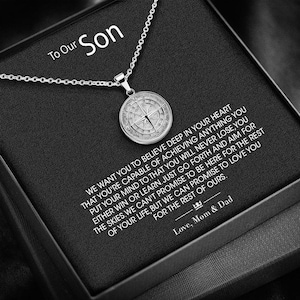 May include: A silver compass necklace with a black box and a message to a son. The message reads, "We want you to believe deep in your heart that you're capable of achieving anything you put your mind to. That you will never lose, you either win or learn. Just go forth and aim for the skies. We can't promise to be here for the rest of your life, but we can promise to love you. Love, Mom & Dad."