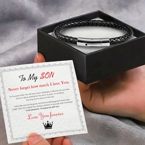 May include: A black leather bracelet with a silver clasp in a gift box with a card that reads "To My Son Never forget how much I love You."  The card has a message about life's challenges and finding the good in every day.  It ends with "Love You forever" and a crown.