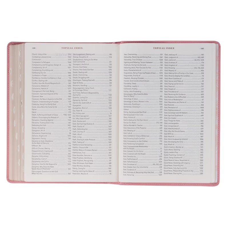 May include: Open Bible with a pink cover, displaying a detailed topical index. The pages are filled with small text, and the book is open to reveal the index. The text is in black, and the book is on a white background.