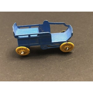 May include: A vintage toy wagon in blue with yellow wheels. The wagon has a simple design with a flat bed and curved sides. The wheels are small and round. The toy appears to be made of metal and shows signs of wear.