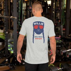 May include: Light gray t-shirt featuring a graphic of a face with red sunglasses, blue beard and braids, and the name "WILLIE" above. Below the face are the words "Blue Skies Red eyes".