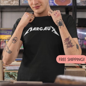 May include: Black t-shirt with the white text "ARGAUX" in a stylized font. The shirt is a crew neck and appears to be made of cotton. The image shows the shirt on a person.