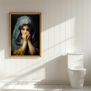 May include: A framed painting of a woman in a blue and gold dress, covering her face with her hands. The painting is set against a white wall.