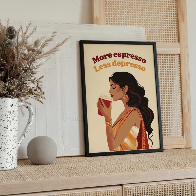 May include: A framed wall art print featuring an illustration of a person with long dark hair holding a red coffee cup. The text "More espresso Less depresso" is printed in dark red and yellow above the figure, who wears gold jewelry.