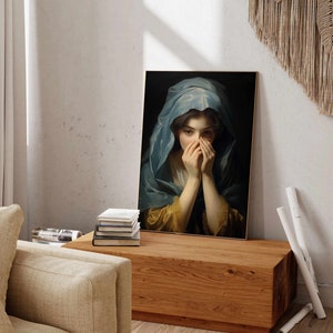 May include: A painting of a woman with her hands covering her face. She is wearing a blue and gold robe and has long dark hair. The painting is framed in a gold frame.