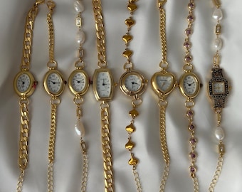 Könnte beinhalten: Eine Sammlung von acht goldfarbenen Armbanduhren mit weißem Zifferblatt und schwarzen Ziffern. Die Uhren haben verschiedene Armbandstile, darunter dicke Panzerketten, herzförmige Glieder, Perlenakzente und kleine violette Steine.