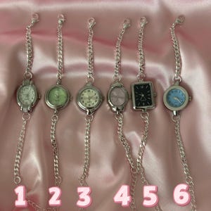 May include: Six silver chain watches with different colored faces, including white, green, pink, and black. The watches have various shapes, including round and square. The numbers 1 through 6 are at the bottom of the image.