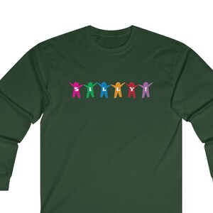 Puede incluir: Una camiseta de manga larga verde oscuro con un gráfico colorido de figuras de palo que se toman de la mano y deletrean "SILLY!"