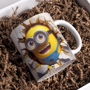 May include: White ceramic mug with a 3D image of a yellow Minion character breaking through a wall. The Minion is wearing blue overalls and goggles and has a big smile.
