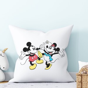 Puede incluir: Almohada blanca con una ilustraci&oacute;n en blanco y negro de Mickey Mouse y Minnie Mouse. Mickey lleva pantalones cortos rojos y zapatos amarillos. Minnie lleva un vestido de lunares azules y blancos y zapatos amarillos.