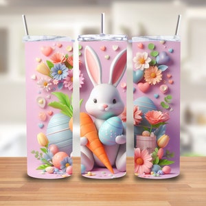 Puede incluir: Tres vasos de acero inoxidable rosas con un tema de Pascua pastel. Cada vaso presenta un conejito blanco sosteniendo una zanahoria y un huevo de Pascua, rodeado de flores pastel, corazones y caramelos.