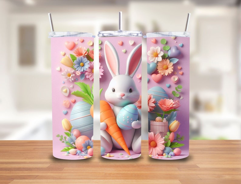 Puede incluir: Tres vasos de acero inoxidable rosas con un tema de Pascua pastel. Cada vaso presenta un conejito blanco sosteniendo una zanahoria y un huevo de Pascua, rodeado de flores pastel, corazones y caramelos.