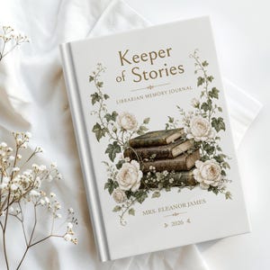May include: A white hardcover journal titled Keeper of Stories Librarian Memory Journal with a central illustration of a stack of three antique books surrounded by white roses and green vines, personalized with the name Mrs. Eleanor James and 2026.