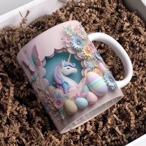 May include: A pink ceramic mug with a 3D paper design featuring a unicorn, flowers, and pastel-colored eggs. The mug has a white handle.