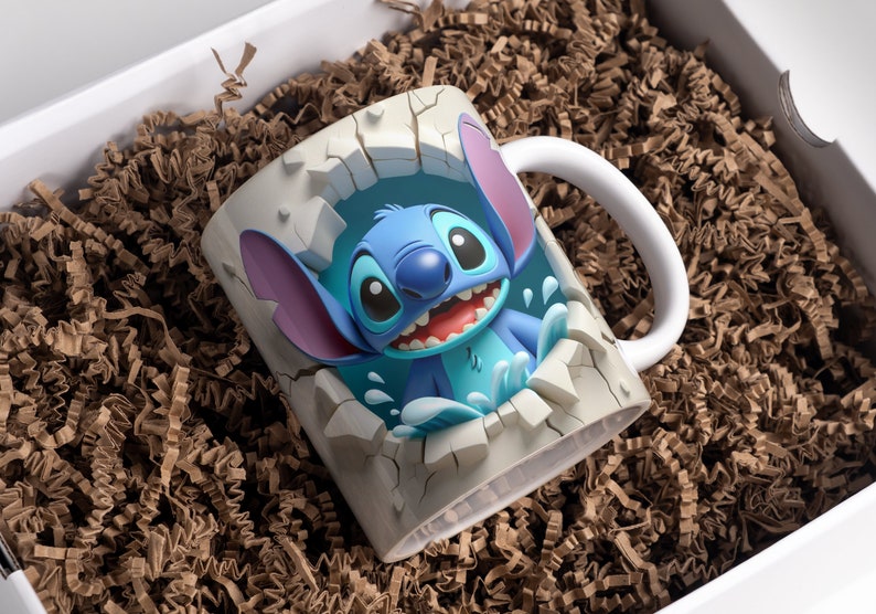 May include: A white ceramic mug with a 3D image of Stitch, a blue alien character from the Disney movie Lilo & Stitch, breaking through the mug. Stitch is smiling and has his signature blue eyes and large ears. The mug is surrounded by brown packing peanuts.