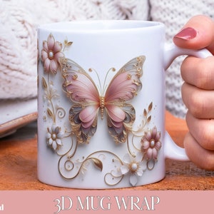 Könnte beinhalten: Weiße Keramiktasse mit einem 3D-Design eines rosa Schmetterlings mit goldenen Akzenten und perlmuttartigen Verzierungen. Der Schmetterling ist von floralen Designs umgeben. Die Tasse ist 15oz oder 11oz.