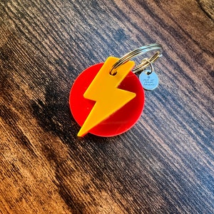 Peut inclure: Un porte-clés en forme d'éclair rouge et jaune avec un charme argenté qui dit "Pour mon meilleur ami".