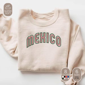 May include: A cream-colored sweatshirt with the word "MEXICO" embroidered in green and red. The sweatshirt has a crew neck and long sleeves. The image also shows the options for 8 colors and 6 sizes.
