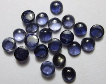Puede incluir: Una colección de piedras preciosas redondas y pulidas en varios tonos de azul oscuro y negro. Las piedras tienen una superficie lisa y reflectante, algunas parecen translúcidas. Las piedras preciosas están dispersas sobre una superficie blanca.