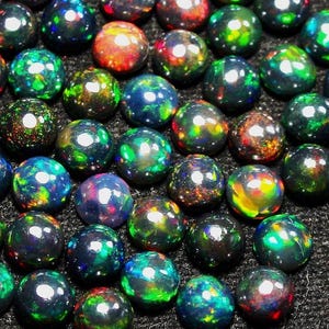 May include: A close-up of numerous black opal spheres, each exhibiting a kaleidoscope of colours. The opals shimmer with green, blue, red, and yellow hues. The spheres are densely packed, highlighting their individual iridescence and overall visual impact.