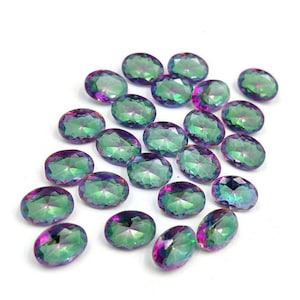 Puede incluir: Un conjunto de gemas de corte ovalado con un gradiente de color vibrante. Las piedras transitan del verde al púrpura, con facetas que capturan la luz. Las gemas están dispersas sobre una superficie blanca, mostrando sus cualidades iridiscentes.