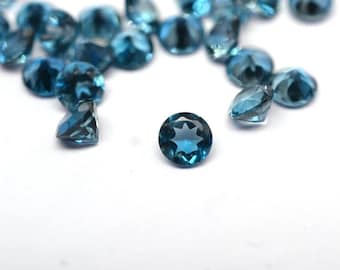 Op de afbeelding: Een verzameling gefacetteerde, ronde, teal-kleurige edelstenen op een witte ondergrond. De edelstenen zijn briljant geslepen en reflecteren het licht. De afbeelding toont de helderheid en kleur van de stenen, ideaal voor sieraden of verzamelen.