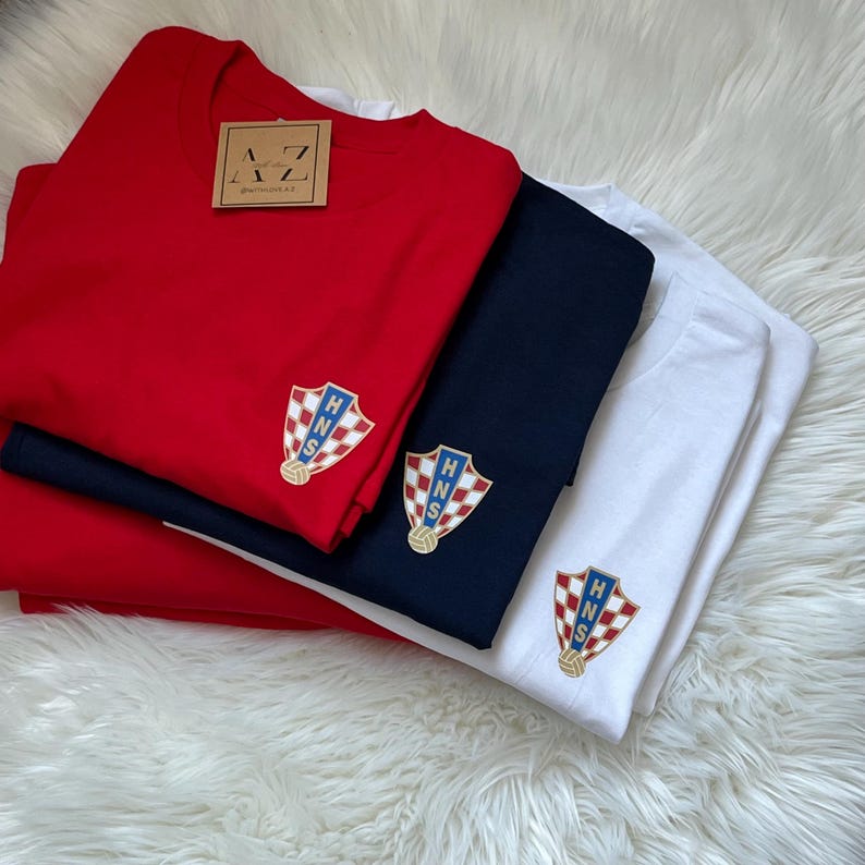 May include: Three t-shirts in red, navy blue, and white, each featuring an embroidered Croatian national football team crest with the letters "HNS" in gold.