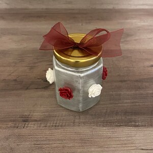 Hand crafted small jar.  Beautifully painted with a metallic silver coating.  Finished off with maroon & white flower accents.  Very classy.