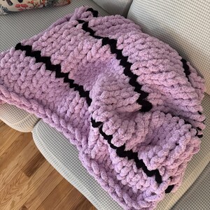 Handgestrickte dunkellila und schwarze grobstrick Kuscheldecke.