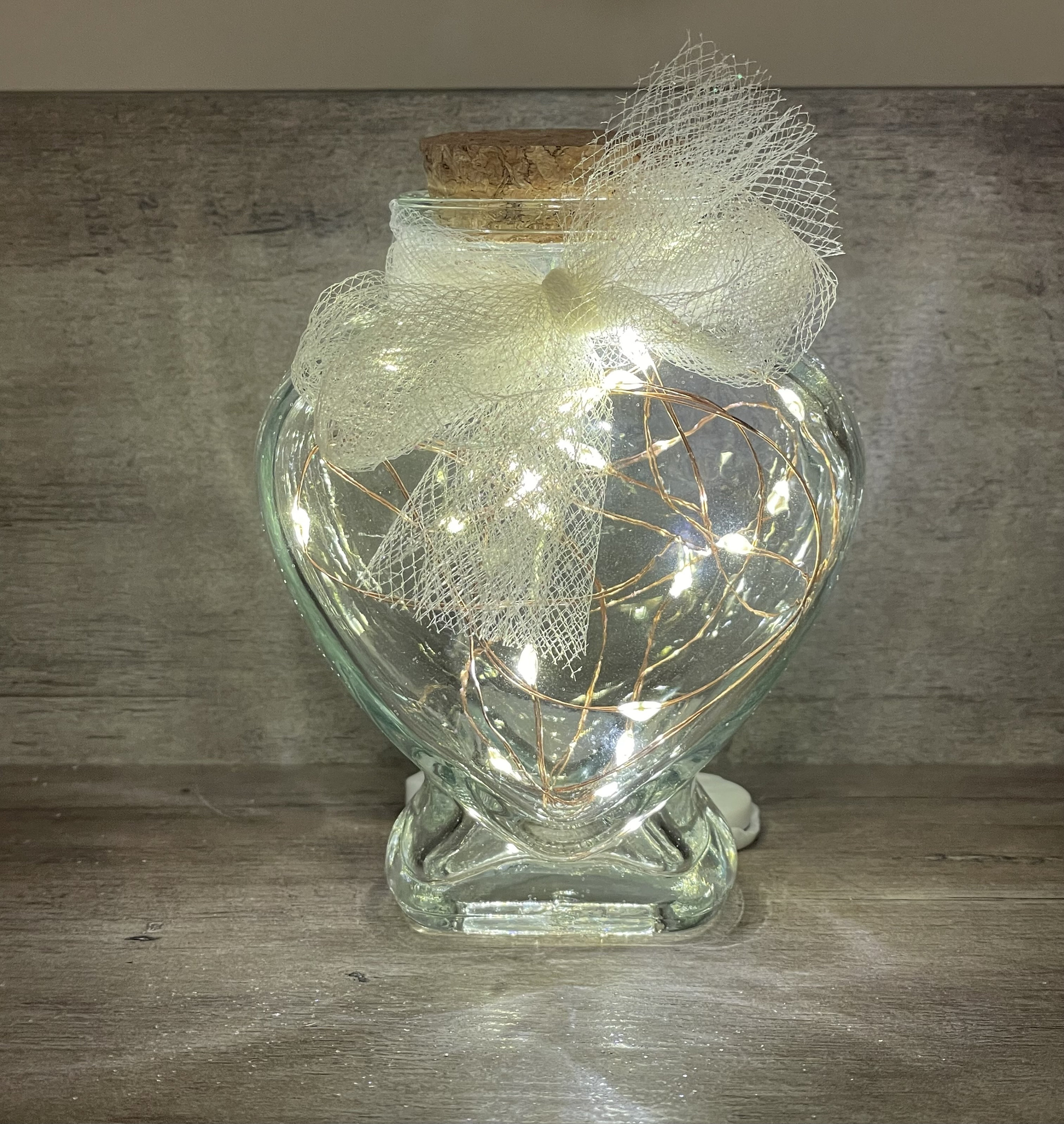 Mini heart shaped glass jar with cork lid and firefly lighting.  Cute gift for Valentine’s Day.  Classy wedding favor idea.
