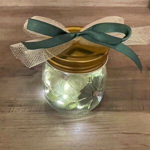 Gorgeous small hand-decorated mason jar with hand painted beach rocks & copper wire firefly lights.  Green theme including silk flowers.